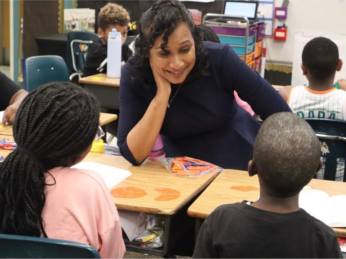 A mentor talking with students at a classroom table
